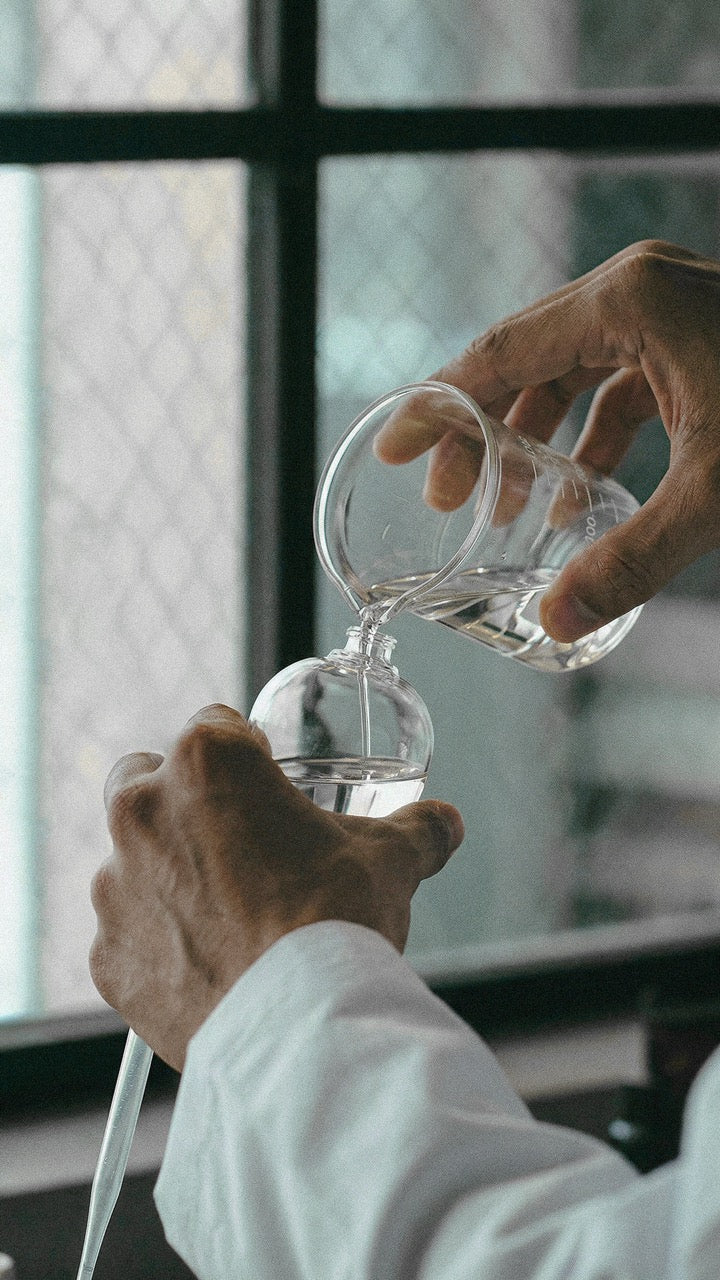 Parfumeur versant un concentré de parfum dans un flacon en verre, création artisanale à Grasse