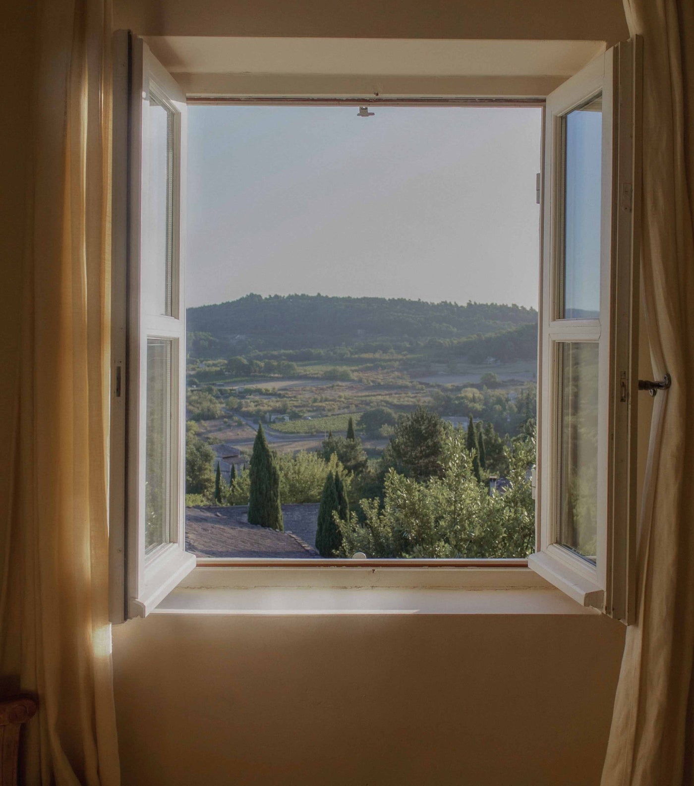 Fenêtre ouverte sur un paysage de collines provençales, évocation du territoire grassois de Parfum d'Éthique