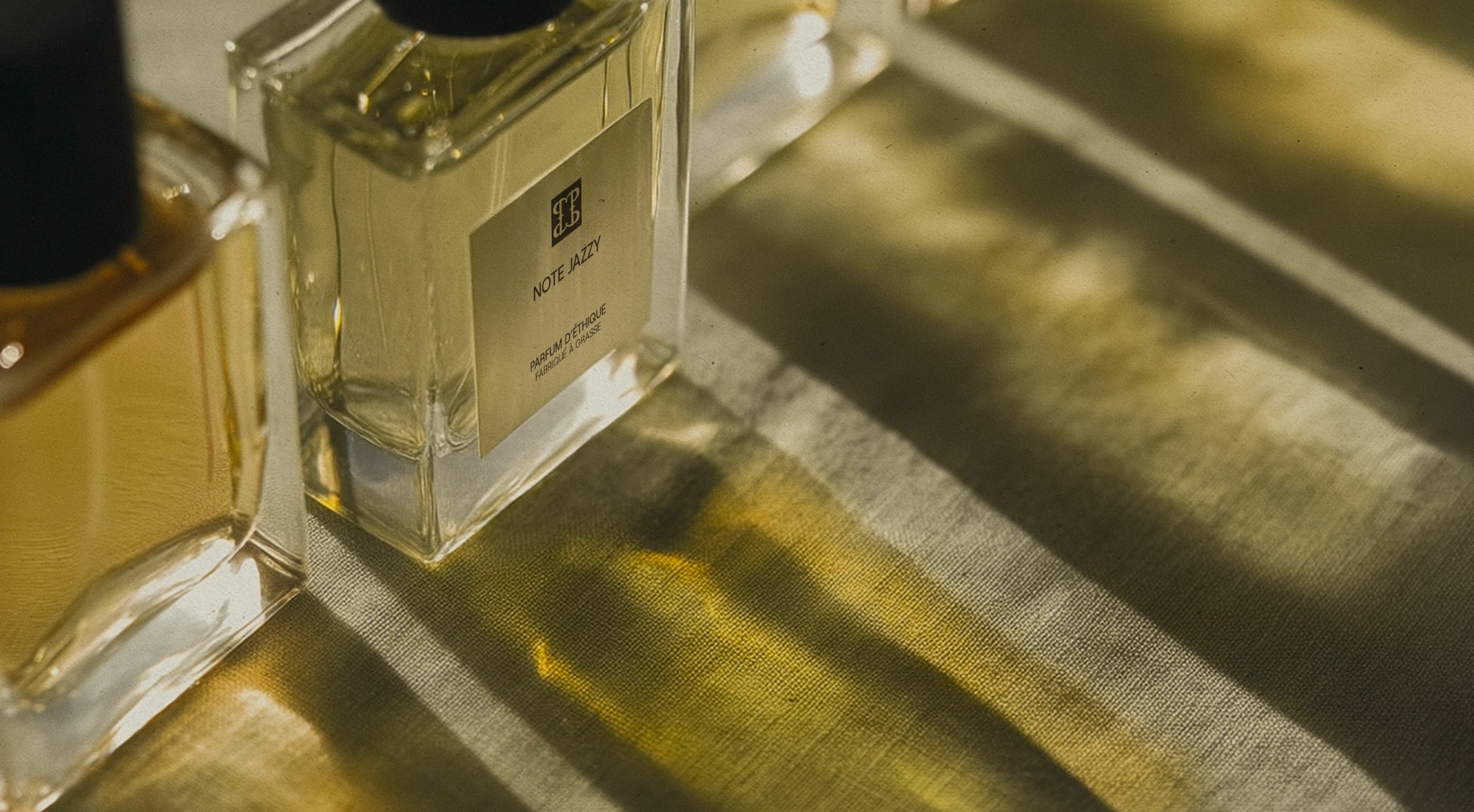 Flacon de parfum de Parfum d'Éthique posé sur tissu doré, parfum de niche issu de stocks dormants de Grasse